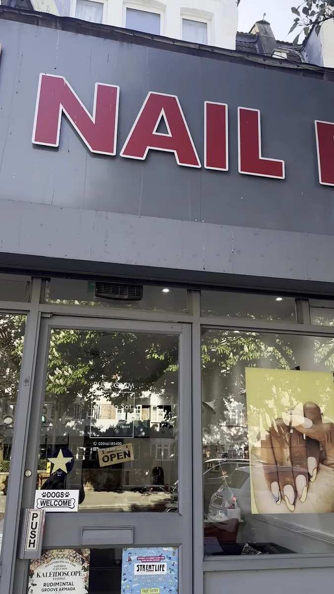 The Busy Glam Nail Bar shopfront on Harringay Ladder, with its red nail sign and glass door.